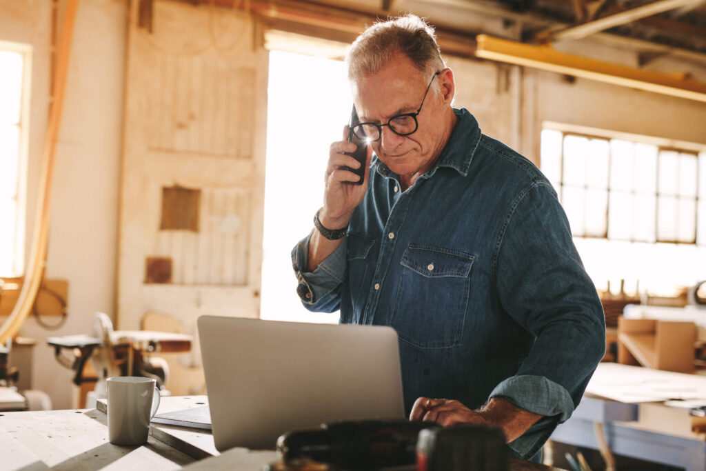 A California small business owner sitting at a desk with documents and a laptop open to a filing checklist, reviewing paperwork for the biennial Statement of Information.