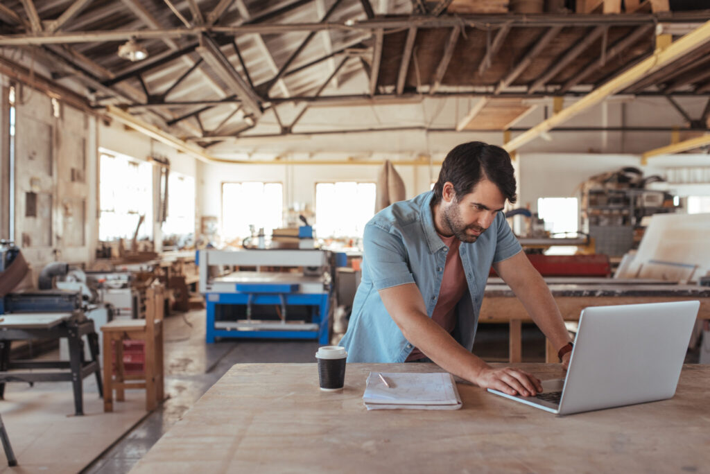 Young woodworker using a laptop in his workshop
